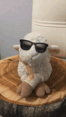 a stuffed sheep wearing sunglasses sits on a wooden table