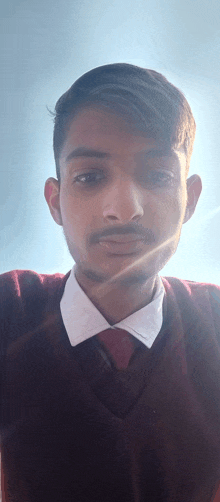 a young man with a beard wearing a red sweater and white shirt