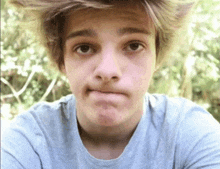 a young man making a funny face while wearing a blue shirt