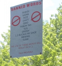 a sign that says " banned words " hangs from a tree