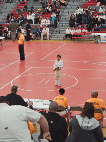 a man in a yellow shirt that says official sits in a wrestling ring