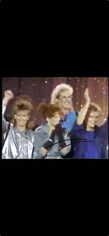 a group of people are standing on a stage with their hands in the air