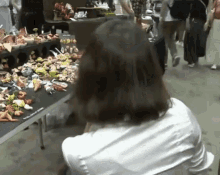 a woman in a white shirt sits in front of a table with a lot of stuffed animals on it