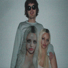 a man wearing sunglasses stands next to two women with their faces painted on their shirts