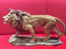 a statue of a lion is on a red surface