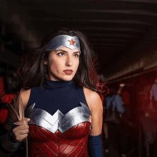 a woman in a wonder woman costume is holding a rope and looking away from the camera .