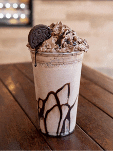 a milkshake in a plastic cup with a cookie on top