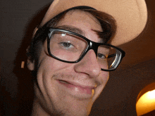 a young man wearing glasses and a hat makes a funny face