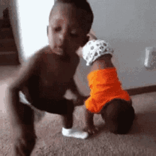 two young boys are playing with a baby on the floor . one of the boys is kissing the baby on the cheek .