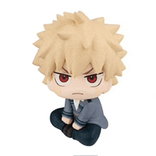 a chibi figurine of a boy with spiky hair and red eyes is sitting on the floor .