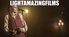 a man in a red vest is singing into a microphone with the words light amazing films above him