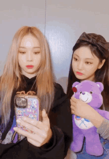 two girls are taking a picture of themselves with a care bear