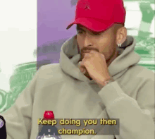 a man wearing a red hat and a hoodie says `` keep doing you then champion ''