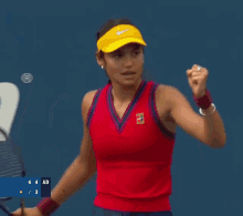 a woman wearing a red tennis outfit and a yellow nike hat