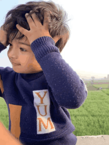 a young boy wearing a blue yum sweater