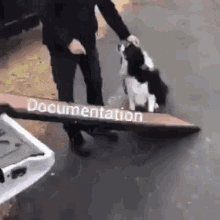 a man is holding a sign that says `` documentation '' next to a dog .