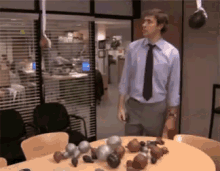 a man in a blue shirt and black tie is standing in front of a table with boxing gloves on it