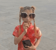 the girl is wearing sunglasses and a red dress and holding a cell phone .