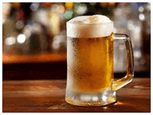 a mug of beer is sitting on a wooden table in a bar .