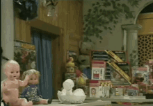 a baby doll sits on a table in front of a display of toys including one that says ' snoopy '