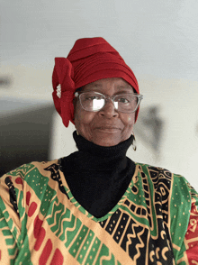 a woman wearing glasses and a red turban has a shirt that says ' african ' on it