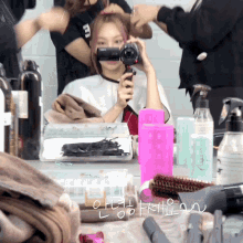 a woman is getting her hair blow dried in front of a mirror with a pink container that says ' a ' on it