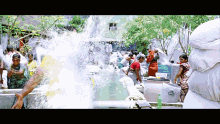 a group of people are standing in front of a water fountain with a bottle of soap in the foreground