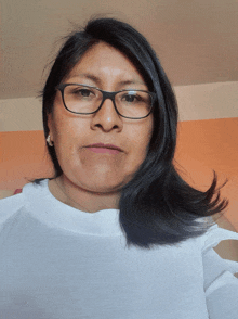 a woman wearing glasses and a white shirt takes a selfie