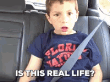 a young boy wearing a florida shirt is sitting in the back seat of a car with his seat belt on .