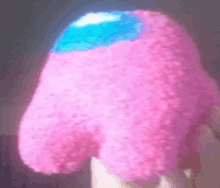 a person is holding a pink among us stuffed animal with a blue face .