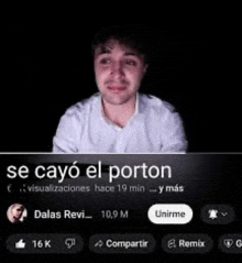 a man in a white shirt is sitting in front of a black screen with a caption in spanish .