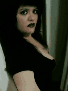 a woman with dark hair and red lipstick is looking at the camera