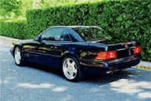 a black sports car is parked on the side of a road .