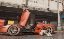 a man is kneeling next to a red sports car in front of a sign that says 6.00 8.15 10.30