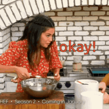 a woman in a red dress is preparing food in a kitchen with the words okay coming in january behind her