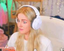 a blonde woman wearing white headphones with the number 3 on the bottom right