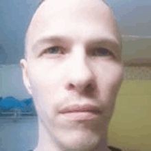 a close up of a man 's face with a bald head and a serious look on his face .