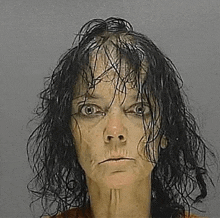 a woman with wet hair is making a funny face in a police mugshot .