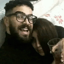 a man with glasses is sitting next to a woman holding a glass of wine .