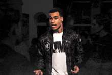 a man wearing a black jacket and a white t-shirt with the word puma on it