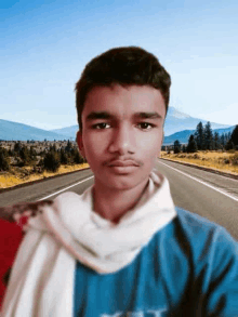 a young man wearing a scarf and a blue shirt is standing in front of a road .