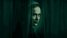 a woman peeking out from behind a green curtain with her eyes closed