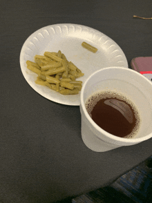 a paper plate with green beans and a cup of coffee