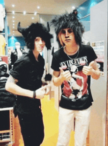 a man wearing a black shirt that says guns n ' roses stands next to another man