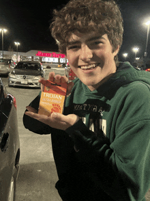 a young man holding a trojan ultra lubricated condom in his hand