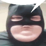 a close up of a person wearing a batman mask with a speech bubble above their head .