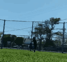 a baseball player stands in front of a chain link fence with a sign that says ' coca cola '