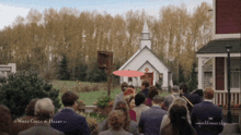 a group of people are gathered in front of a small church with a sign that says hallmark on it