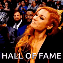 a woman in a black dress is sitting in a crowd with the words hall of fame written above her .