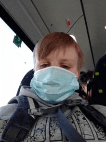 a young boy is wearing a face mask on a bus .